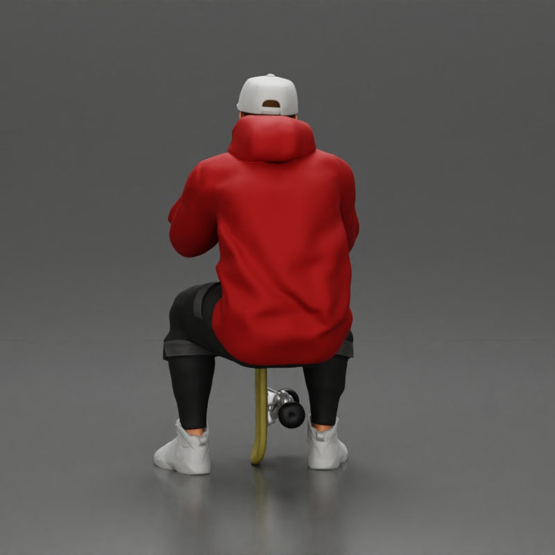 man in hoodie and cap sitting and putting his hand on the skateboard