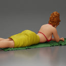 Relaxing on a beach towel, a woman enjoys sunbathing, wrapped in a pareo beach cover and bikini - Only-Games