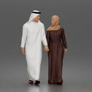 Walking man wearing thobe holding hands with woman wearing abaya