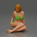 Woman in green bikini sitting gracefully on the floor with a relaxed pose - Only-Games