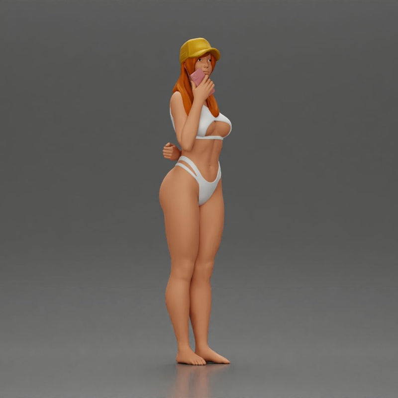 girl in a white bikini holding a phone on the beach and wearing a cap - Only-Games