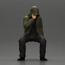 Man in hooded jacket sits alone holding gun feeling troubled - Only-Games