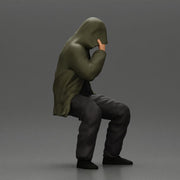 Man in hooded jacket sits alone holding gun feeling troubled - Only-Games