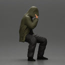 Man in hooded jacket sits alone holding gun feeling troubled - Only-Games