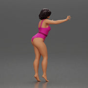 Woman with short black hair wearing pink swimsuit raising arms - Only-Games