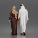 Walking man wearing thobe holding hands with woman wearing abaya