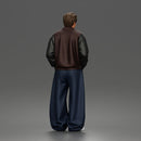 Urban male standing in varsity jacket and baggy trousers