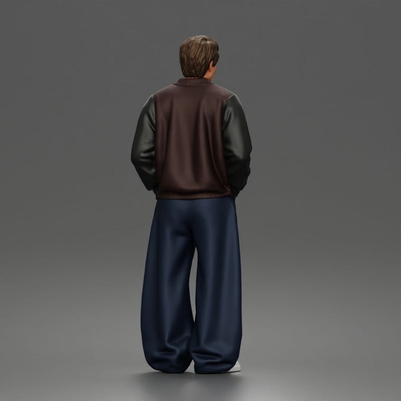 Urban male standing in varsity jacket and baggy trousers