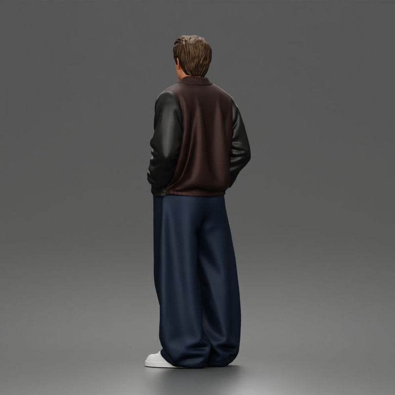 Urban male standing in varsity jacket and baggy trousers