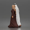 Walking man wearing thobe holding hands with woman wearing abaya