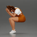 Crying girl sitting low in orange dress with head in hands - Only-Games