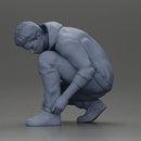 Man in hoodie crouching down tying shoelaces focused in casual outfit - Only-Games