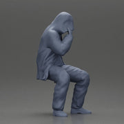 Man in hooded jacket sits alone holding gun feeling troubled - Only-Games