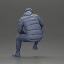 Street performer crouching low in blue puffer jacket athletic stance sitting - Only-Games