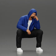 Thoughtful Man in Hoodie Squatting with Hand on His Face - Only-Games