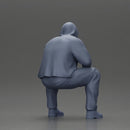 Thoughtful Man in Hoodie Squatting with Hand on His Face - Only-Games