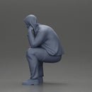 Thoughtful Man in Hoodie Squatting with Hand on His Face - Only-Games