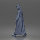 Walking man looking aside wearing traditional thobe headscarf and sandals
