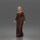 Standing woman looking aside wearing hijab and long belted abaya