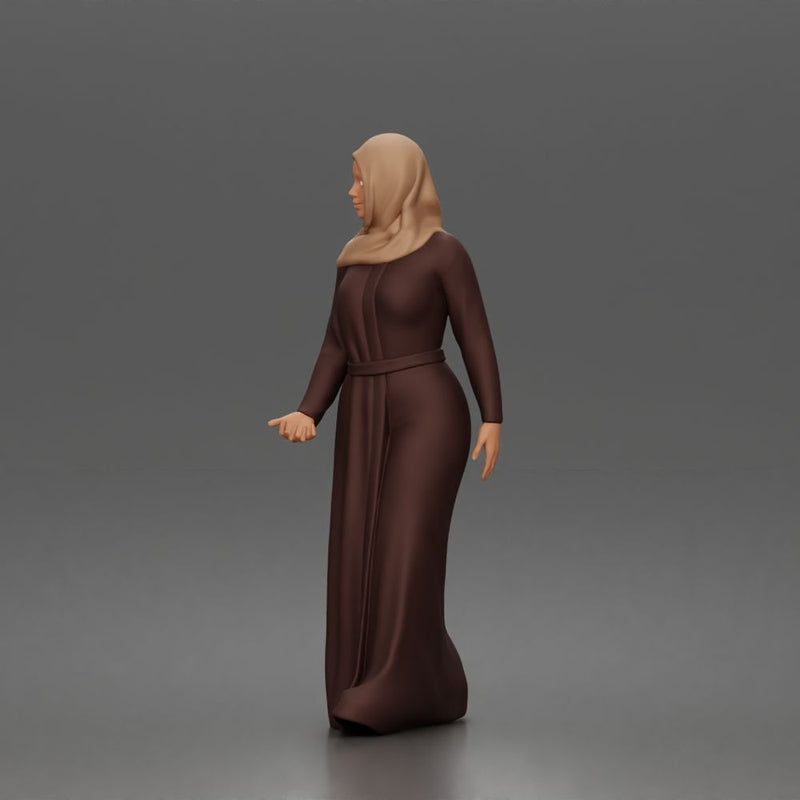 Standing woman looking aside wearing hijab and long belted abaya