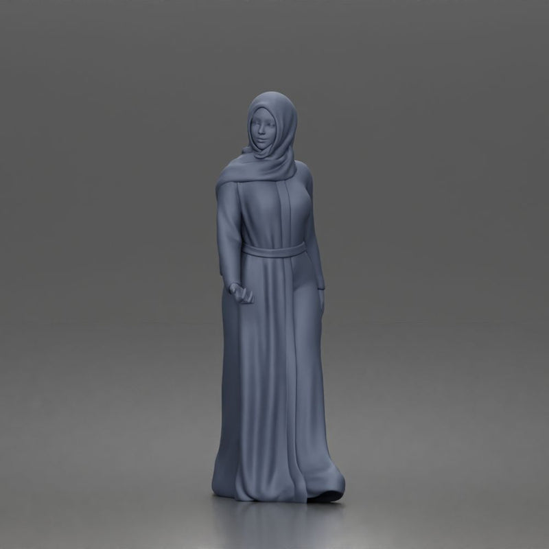 Standing woman looking aside wearing hijab and long belted abaya