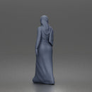 Standing woman looking aside wearing hijab and long belted abaya