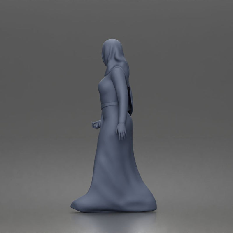 Standing woman looking aside wearing hijab and long belted abaya