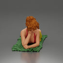 Relaxing on a beach towel, a woman enjoys sunbathing, wrapped in a pareo beach cover and bikini - Only-Games