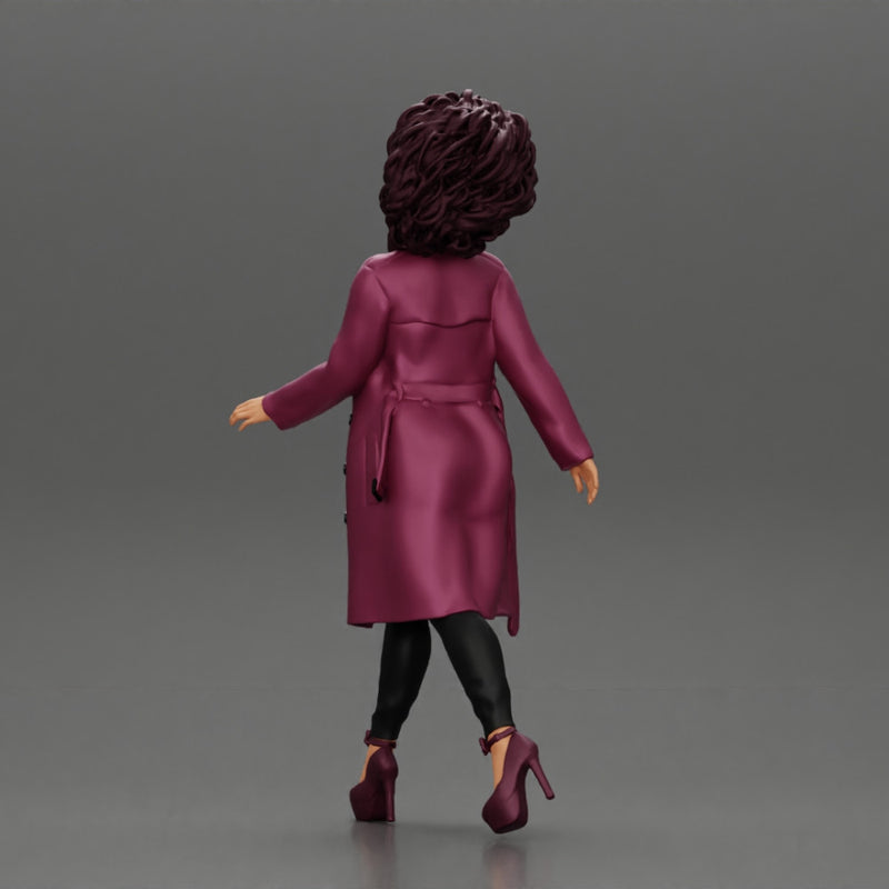 Stylish beautiful woman with curly hair in a fashion long open coat walks on the street