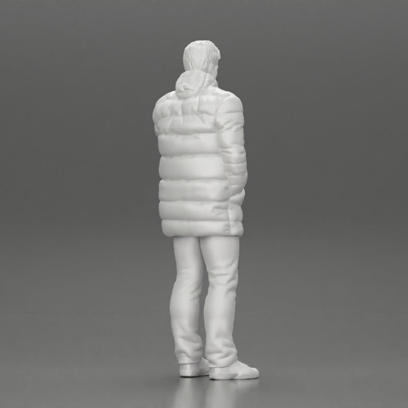 Man in long puffer jacket standing with his hand in his pocket lost in thought