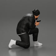 Gangster in hat and jacket sitting and holding a gun hides behind the car - Only-Games