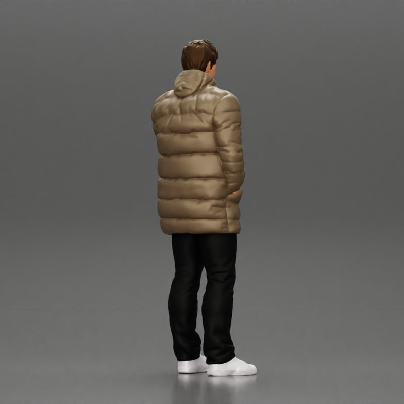 Man in long puffer jacket standing with his hand in his pocket lost in thought