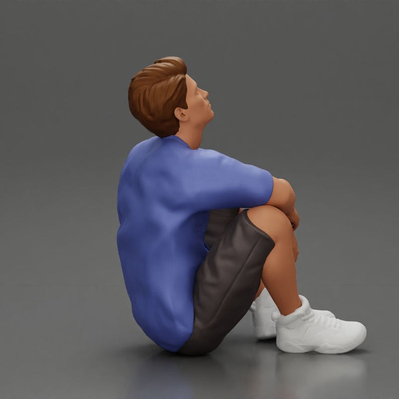 man sitting in shorts on the floor with hands on his knees