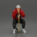 man in hoodie and cap sitting and putting his hand on the skateboard - Only-Games