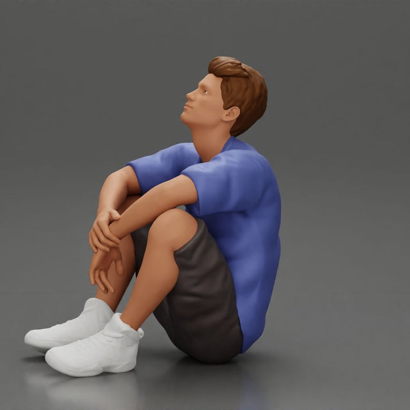 man sitting in shorts on the floor with hands on his knees - Only-Games