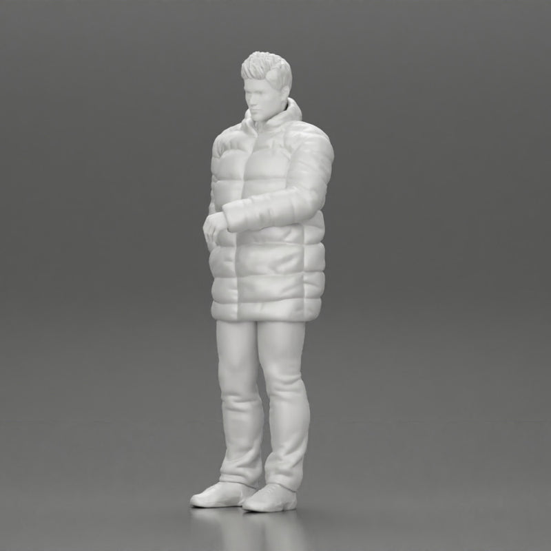 Man in long puffer jacket standing with his hand in his pocket lost in thought