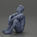 man sitting in shorts on the floor with hands on his knees - Only-Games