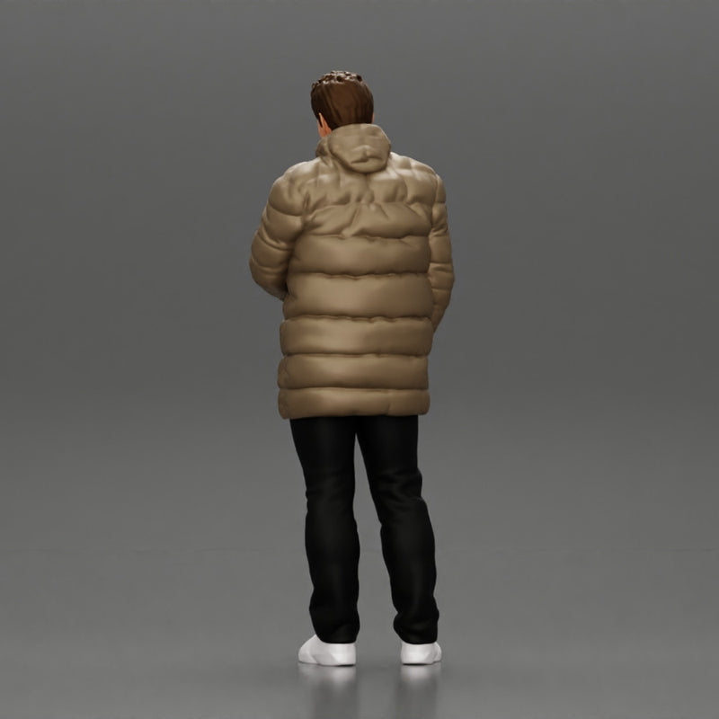 Man in long puffer jacket standing with his hand in his pocket lost in thought