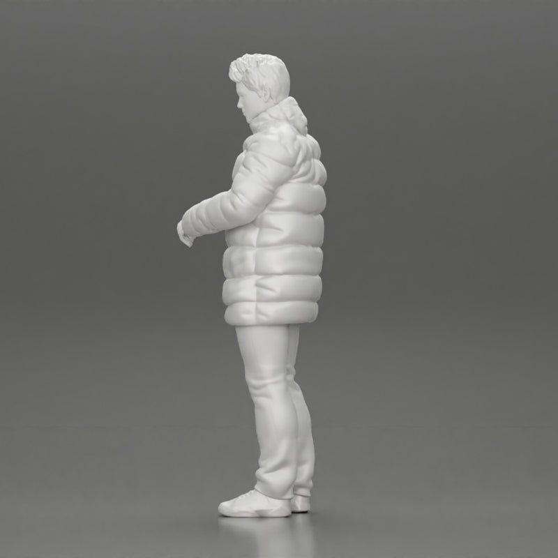 Man in long puffer jacket standing with his hand in his pocket lost in thought