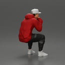 man in hoodie and cap sitting and putting his hand on the skateboard - Only-Games