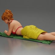Relaxing on a beach towel, a woman enjoys sunbathing, wrapped in a pareo beach cover and bikini - Only-Games