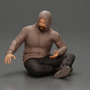 Contemplative man in hoodie sitting cross-legged, expressing curiosity thoughtfully - Only-Games