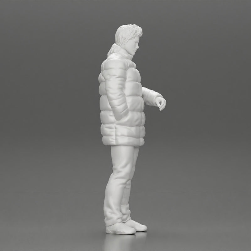 Man in long puffer jacket standing with his hand in his pocket lost in thought