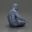 Contemplative man in hoodie sitting cross-legged, expressing curiosity thoughtfully - Only-Games