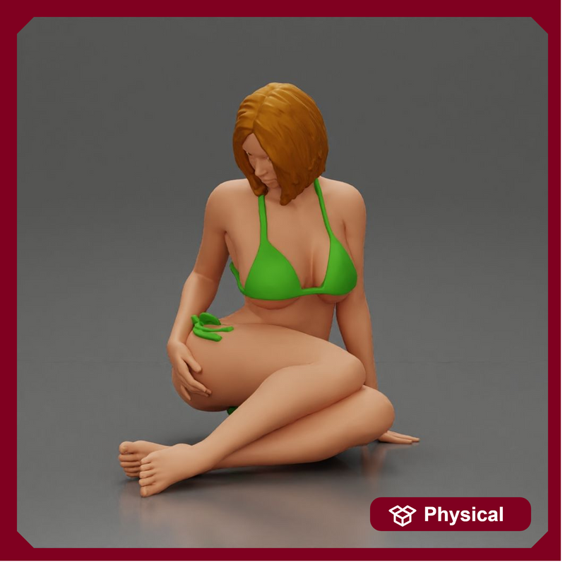 Woman in green bikini sitting gracefully on the floor with a relaxed pose