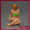 Woman in green bikini sitting gracefully on the floor with a relaxed pose