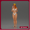 girl in a white bikini holding a phone on the beach and wearing a cap