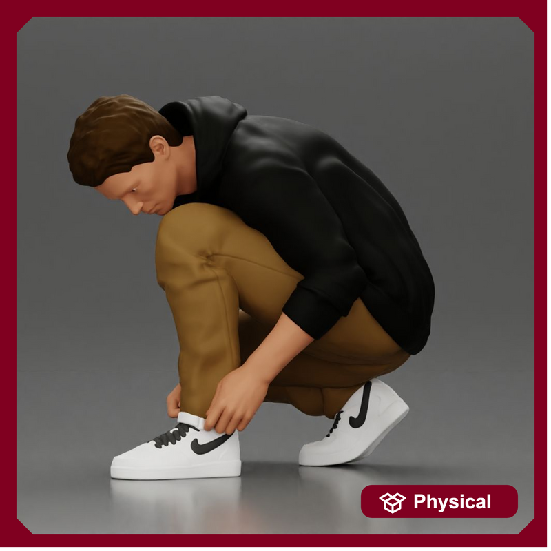 Man in hoodie crouching down tying shoelaces focused in casual outfit